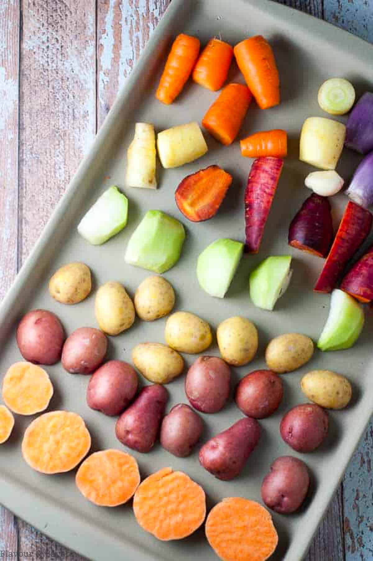 a stoneware baking sheet with rows of root vegetables
