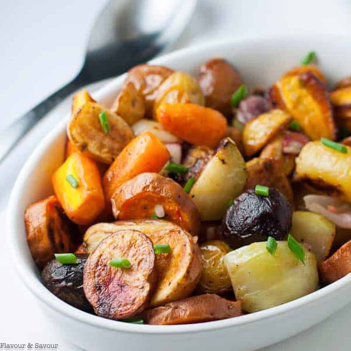 An oval bowl filled with roasted root vegetables.