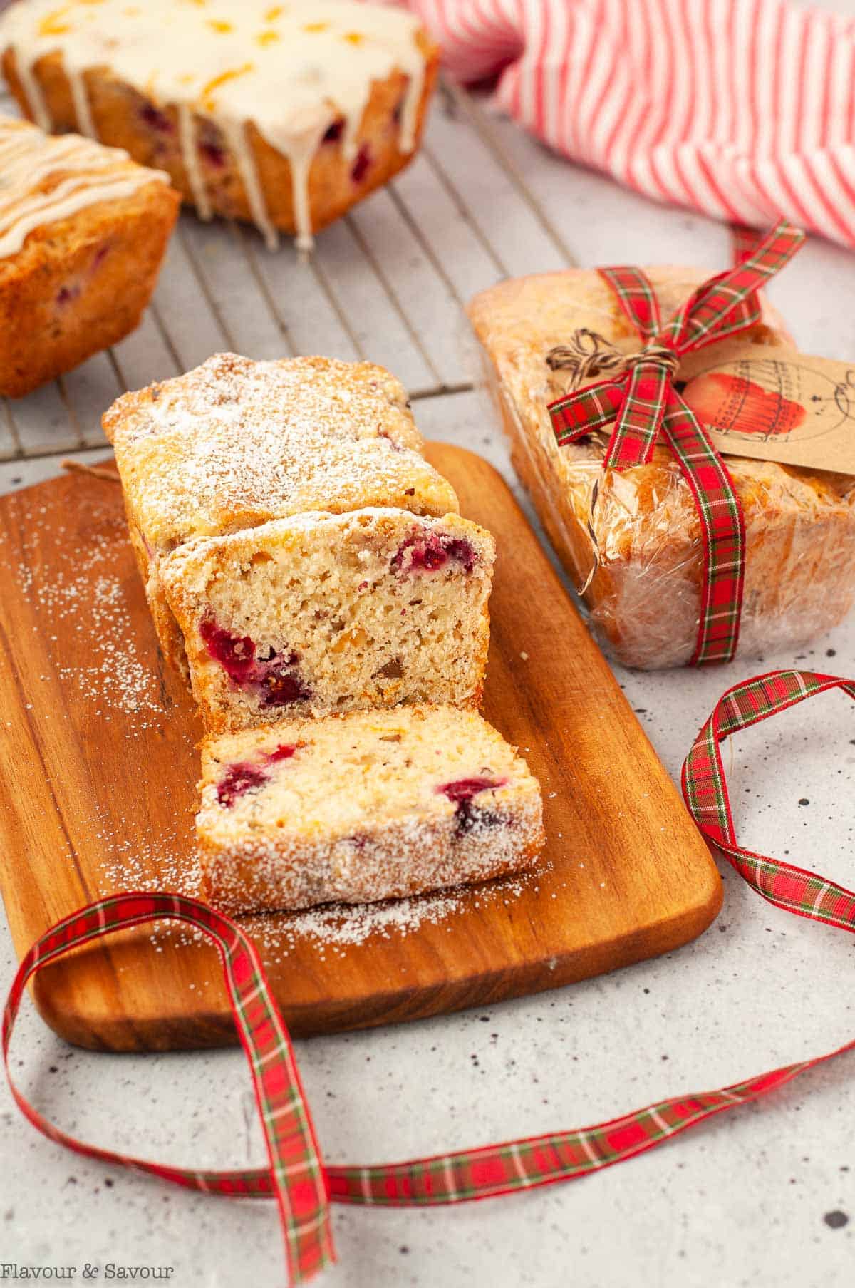 four mini loaves of cranberry orange bread, one wrapped with a ribbon