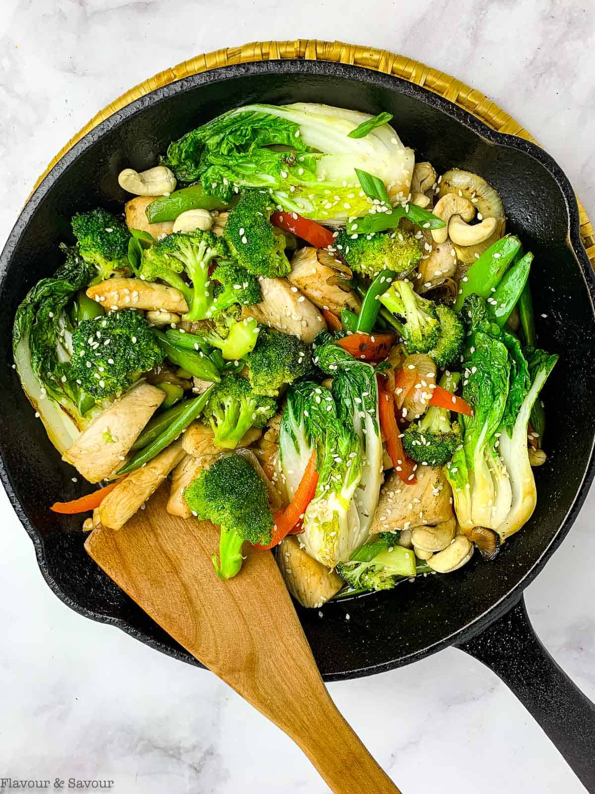 Japanese chicken stir fry in a cast iron skillet with a wooden spatula.