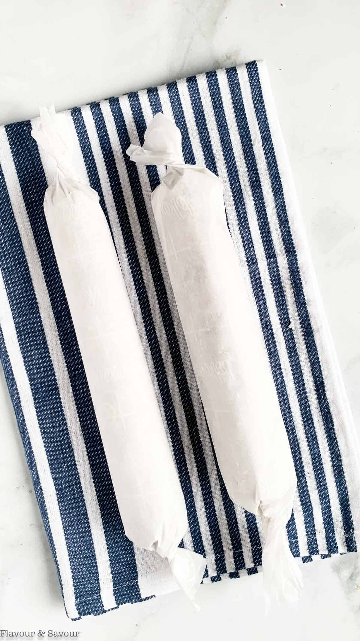 Two date logs tightly wrapped with parchment paper.