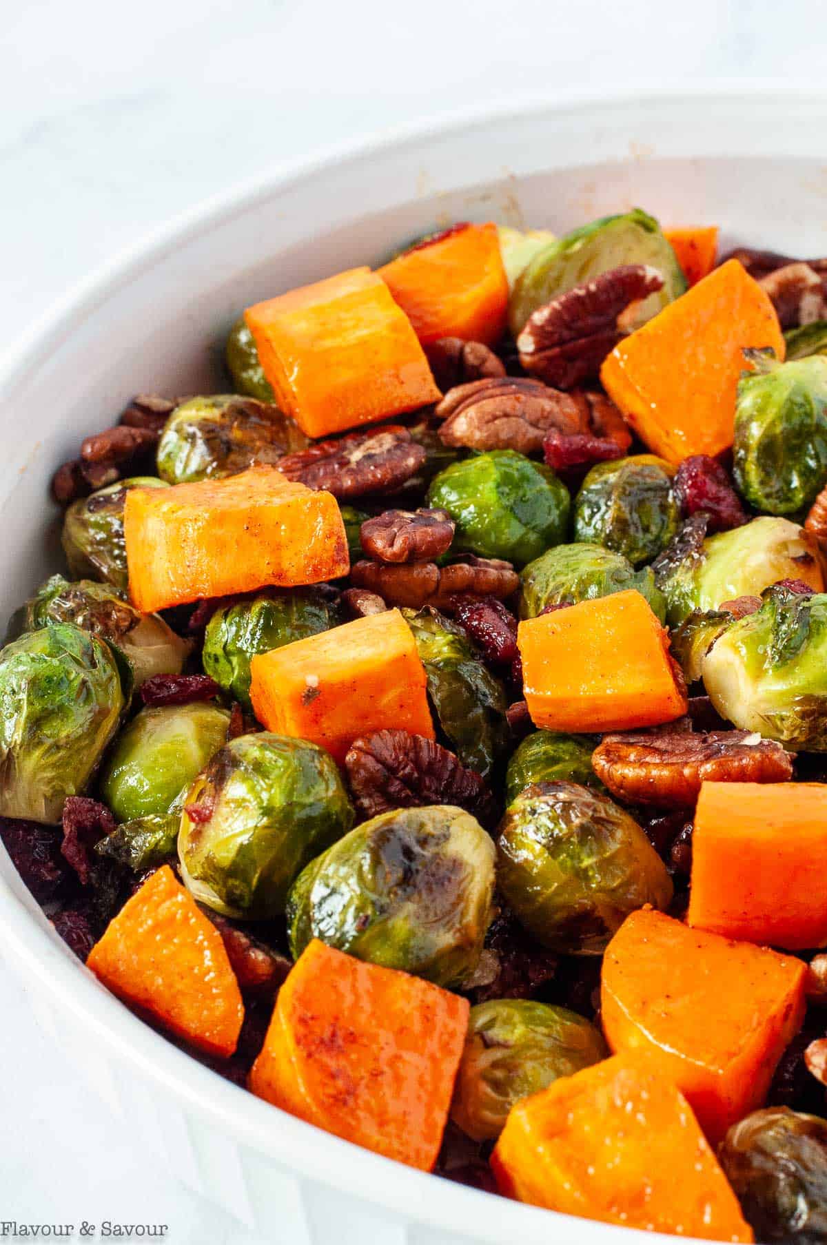 a bowl with roasted Brussels sprouts, maple-glazed sweet potatoes, toasted pecans and dried cranberries.