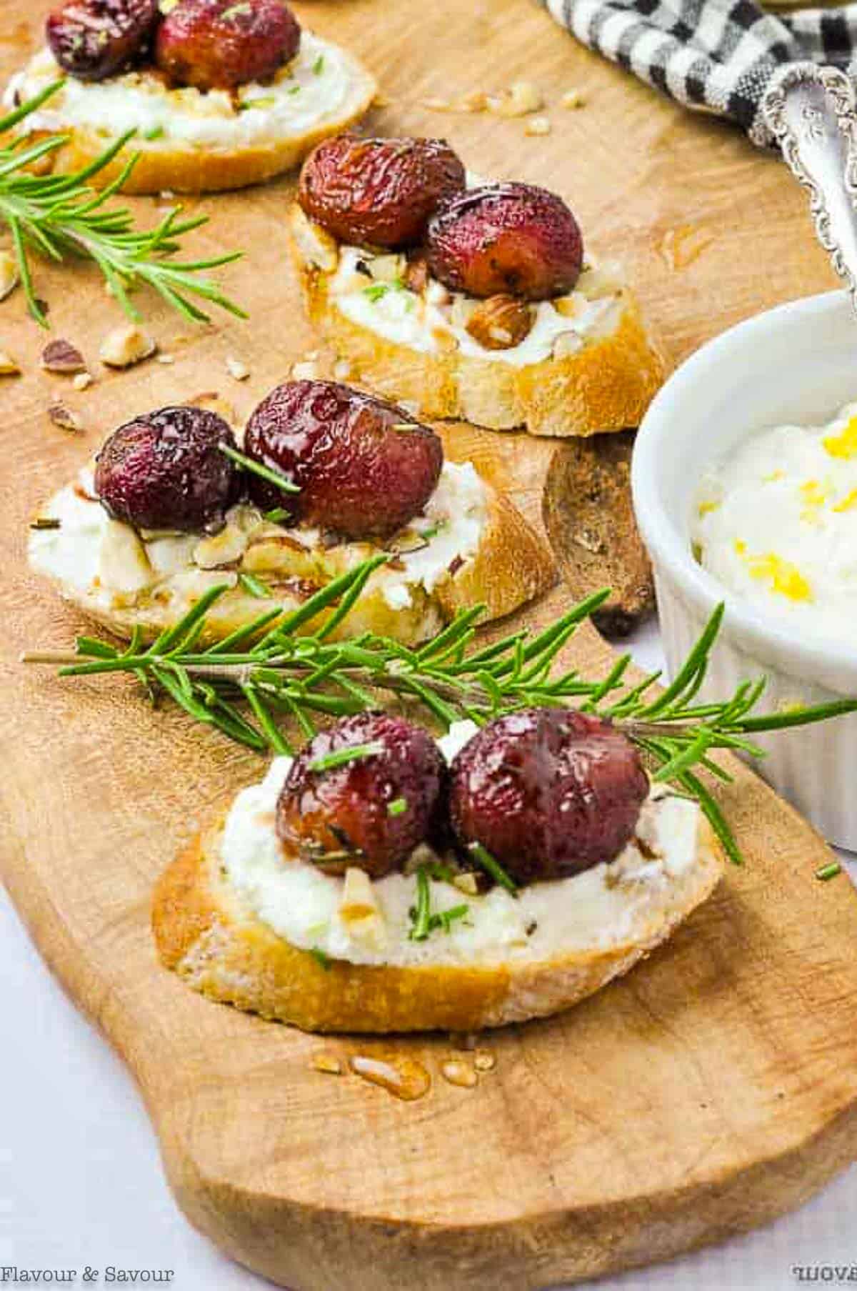 Roasted grape and goat cheese crostini appetizers on a serving board.