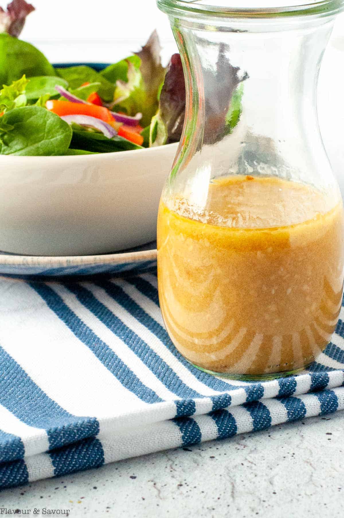 close up view of a jar of miso dressing with sesame seeds