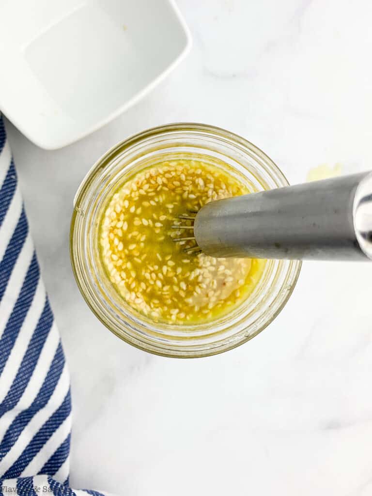 Whisking sesame miso vinaigrette with sesame seeds.