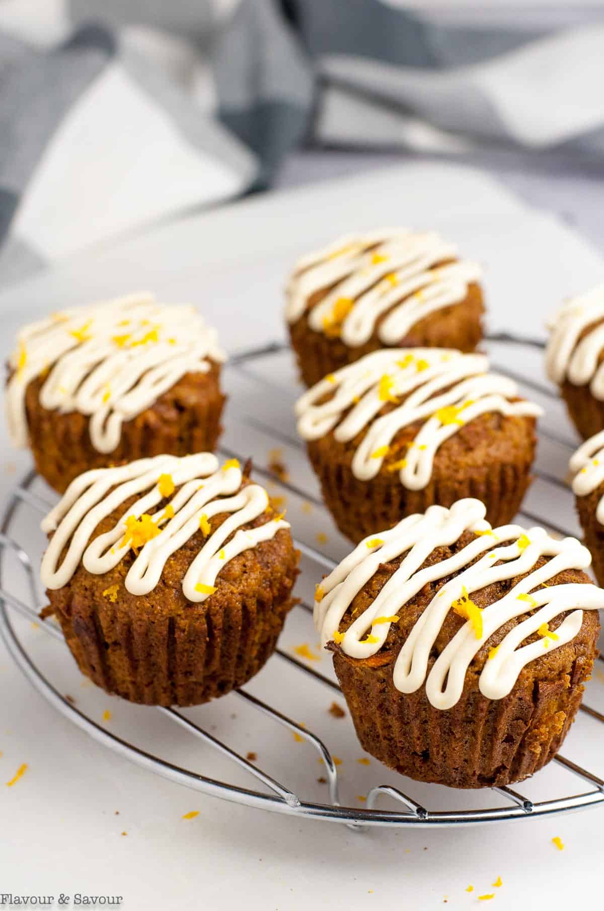 carrot ginger muffins with cream cheese glaze on a cooling rack