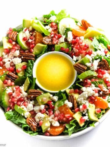 Overhead view of a Christmas Wreath Salad with romaine, avocado, oranges, pecans and feta.