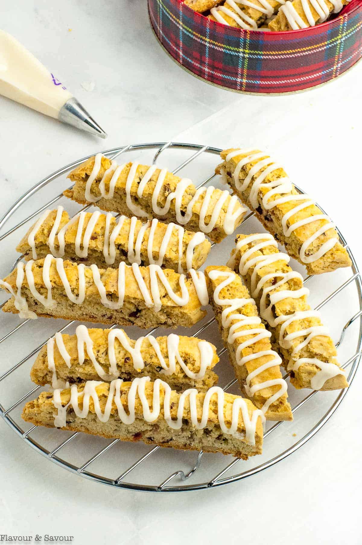 cranberry pecan biscotti on a wire rack with a cookie tin nearby