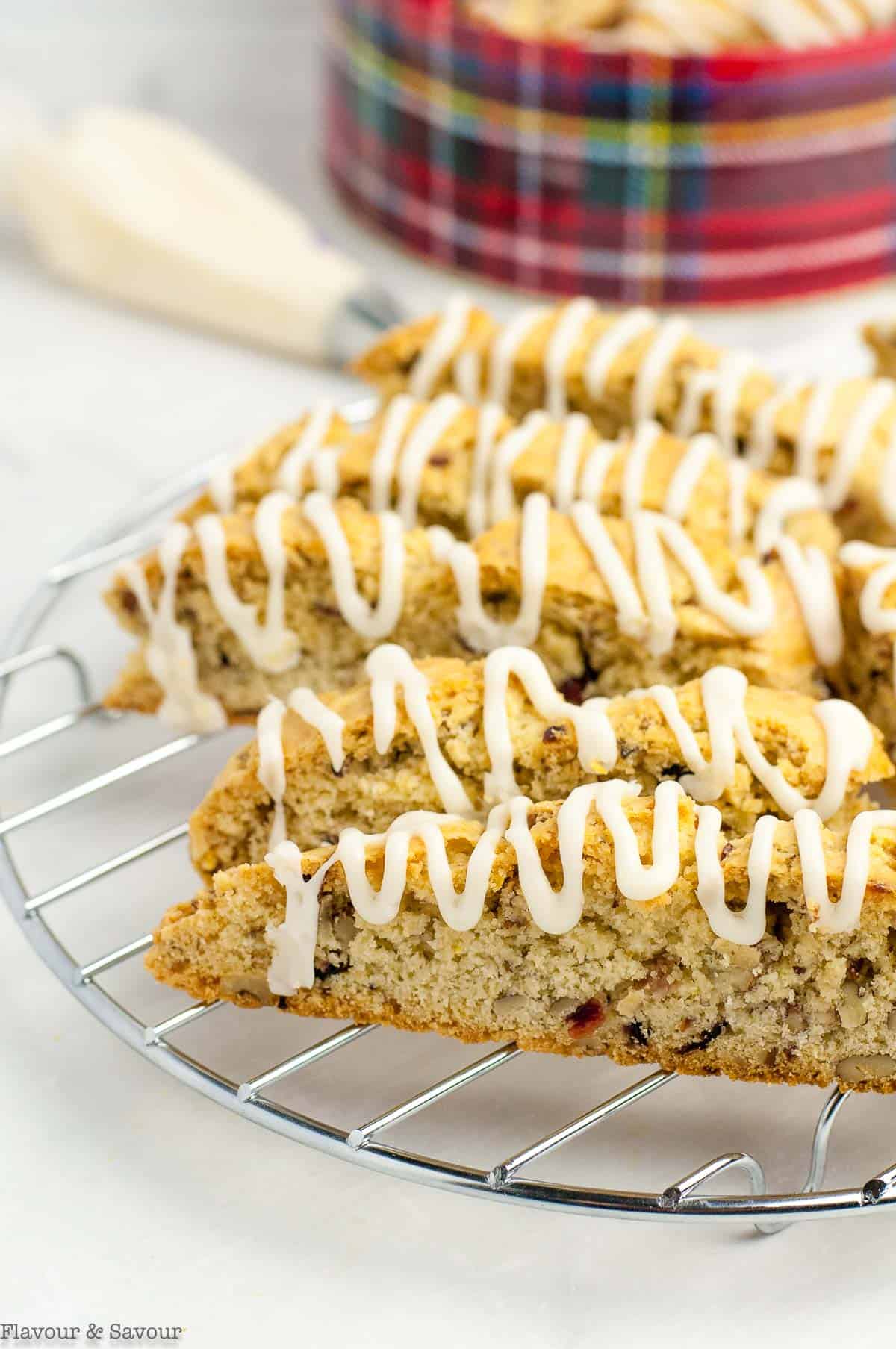 Biscotti slices on a wire rack with a cookie tin in the background.