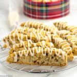 slices of cranberry pecan biscotti on a rack with a cookie tin beside them