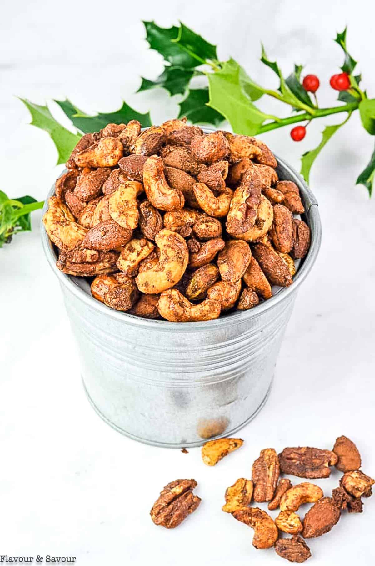 A tin of gingerbread spiced nuts and a sprig of fresh holly.