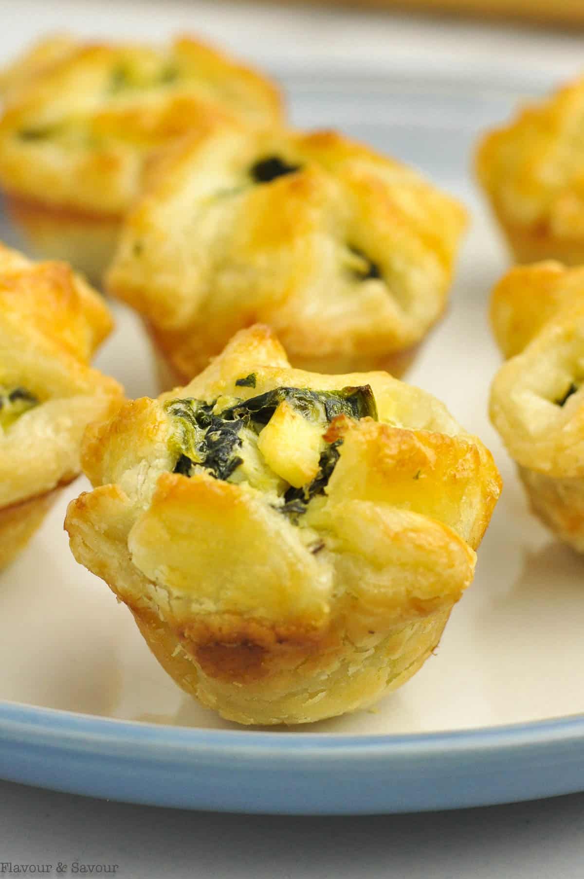Puff pastry appetizers with spinach artichoke filling on a plate.