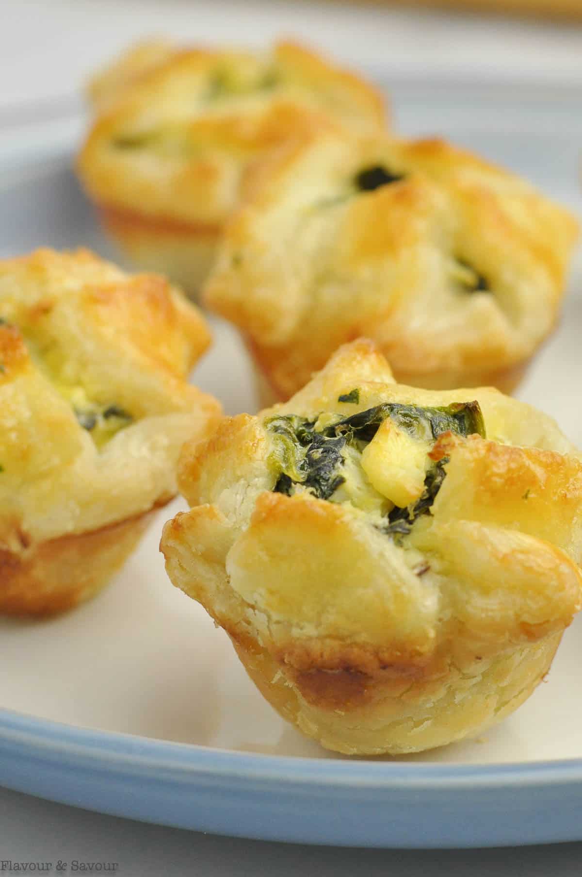 Spinach artichoke puff pastry cups on a blue plate.