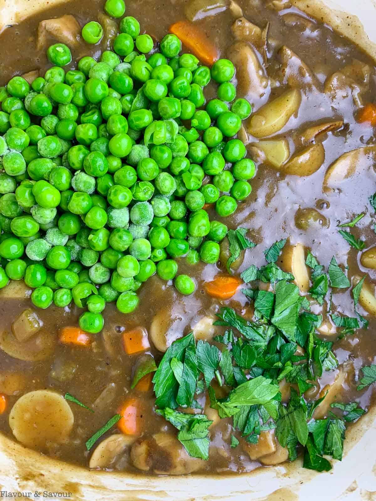 adding frozen peas and parsley to the filling for vegetarian puff pastry pot pie