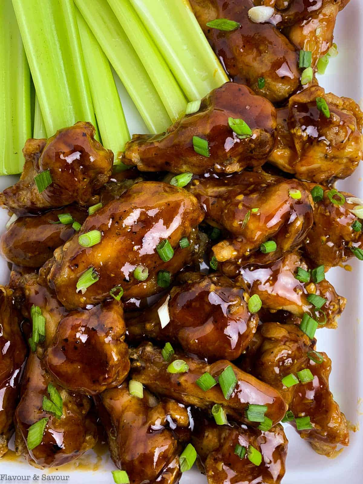 A platter of air fryer honey garlic chicken wings with celery sticks. Ideal for game day snacks.
