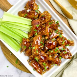 Overhead view of air fryer honey garlic chicken wings served with celery sticksl