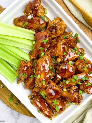 Overhead view of air fryer honey garlic chicken wings served with celery sticksl