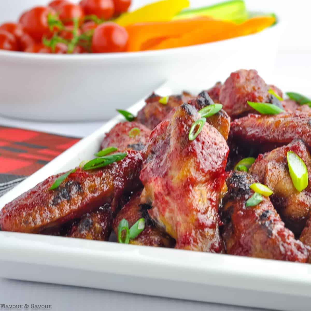 cClose up view of cranberry glazed chili chicken wings in a white platter.