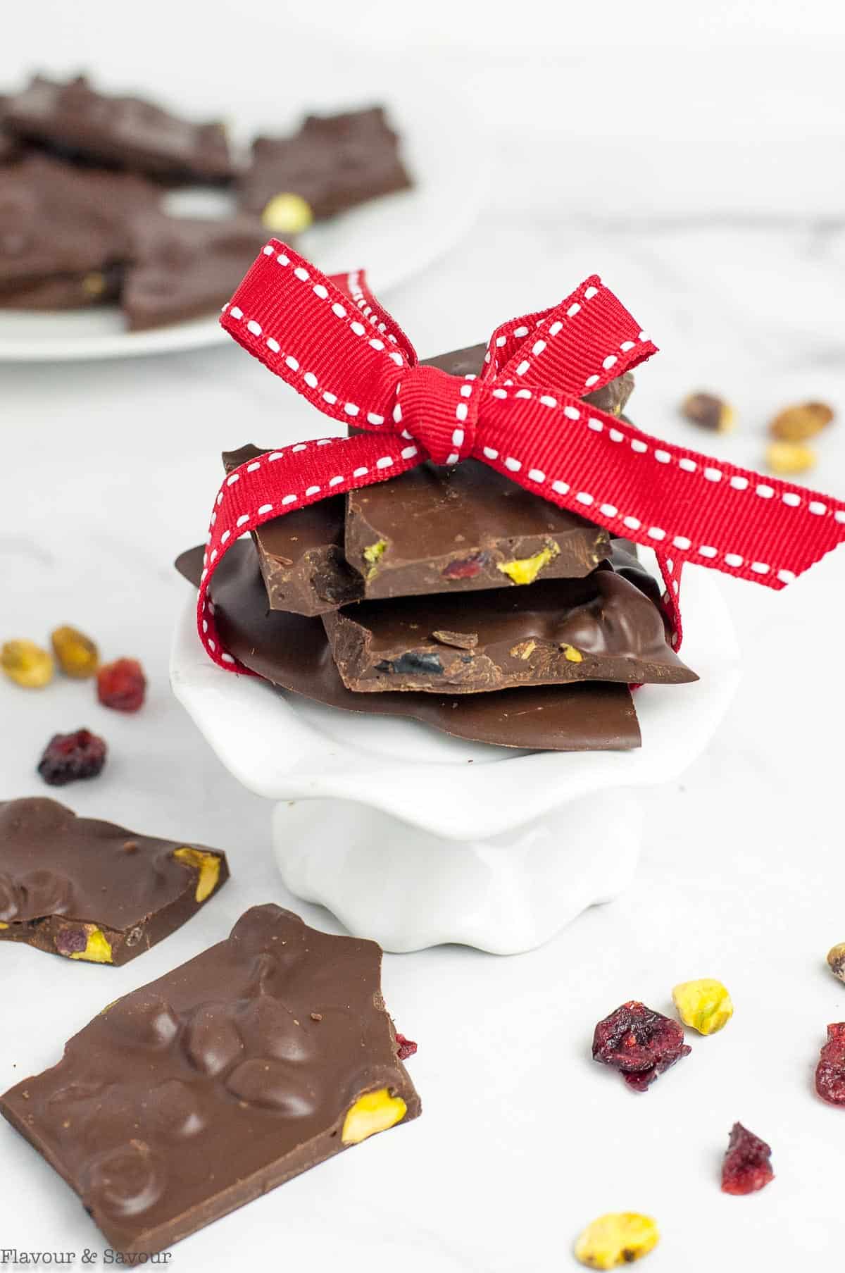 A stack of pieces of cranberry pistachio chocolate bark tied with a red ribbon for a food gift.