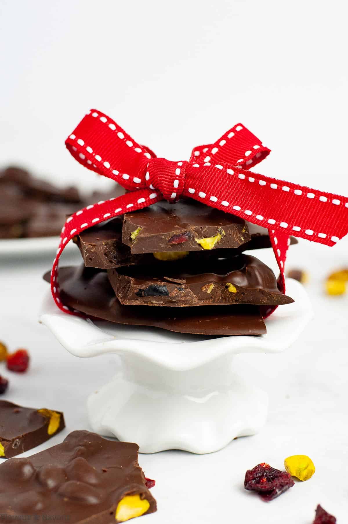 a stack of pieces of cranberry pistachio chocolate bark tied with a red ribon