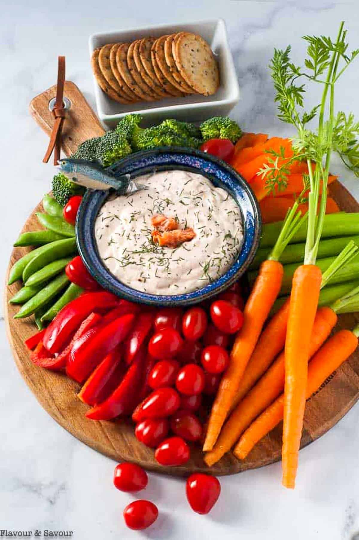 a platter of fresh veggies surrounding a bowl of smoked salmon whipped feta dip