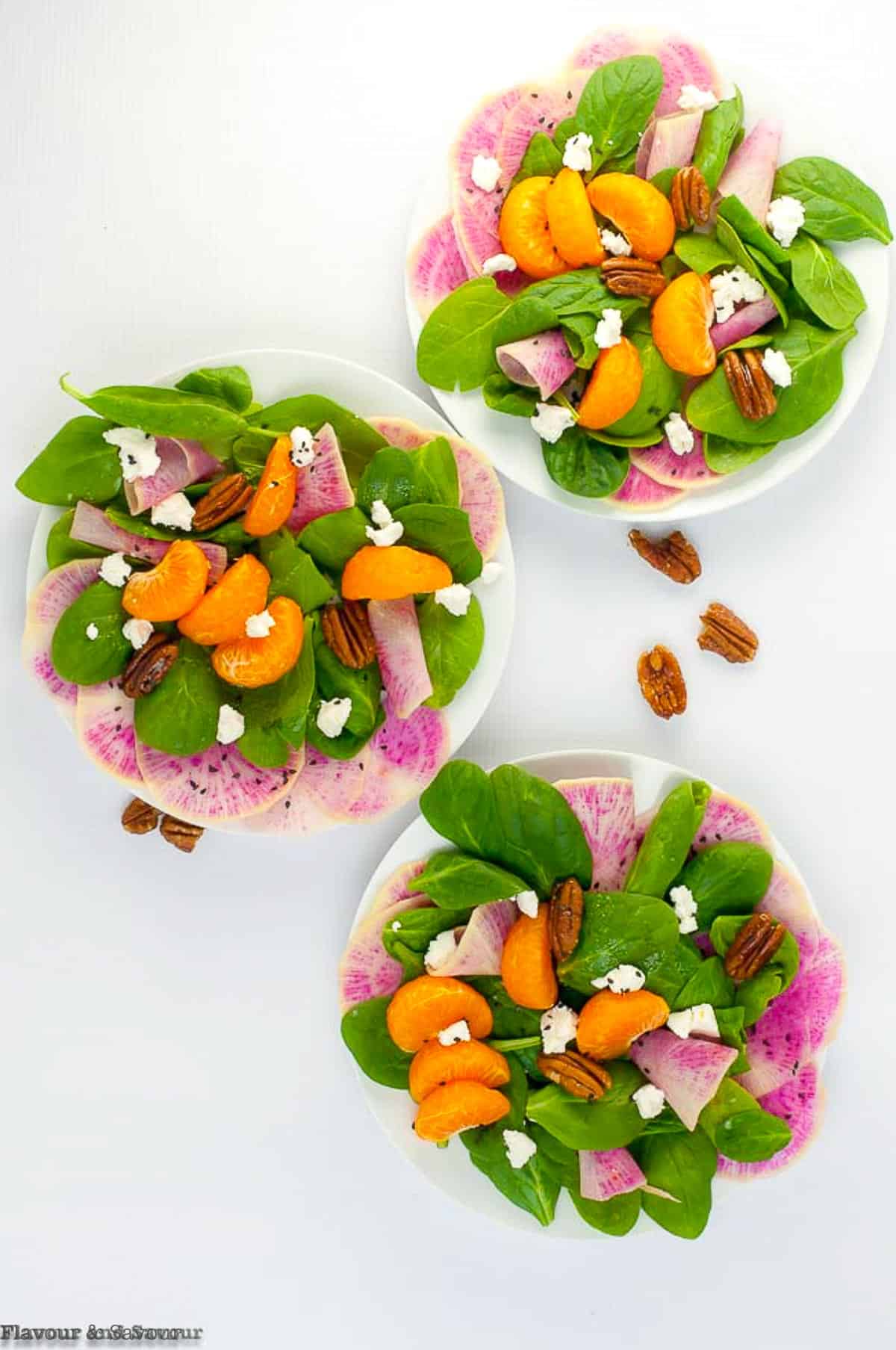 Three plates of winter salads with  watermelon radishes and oranges.