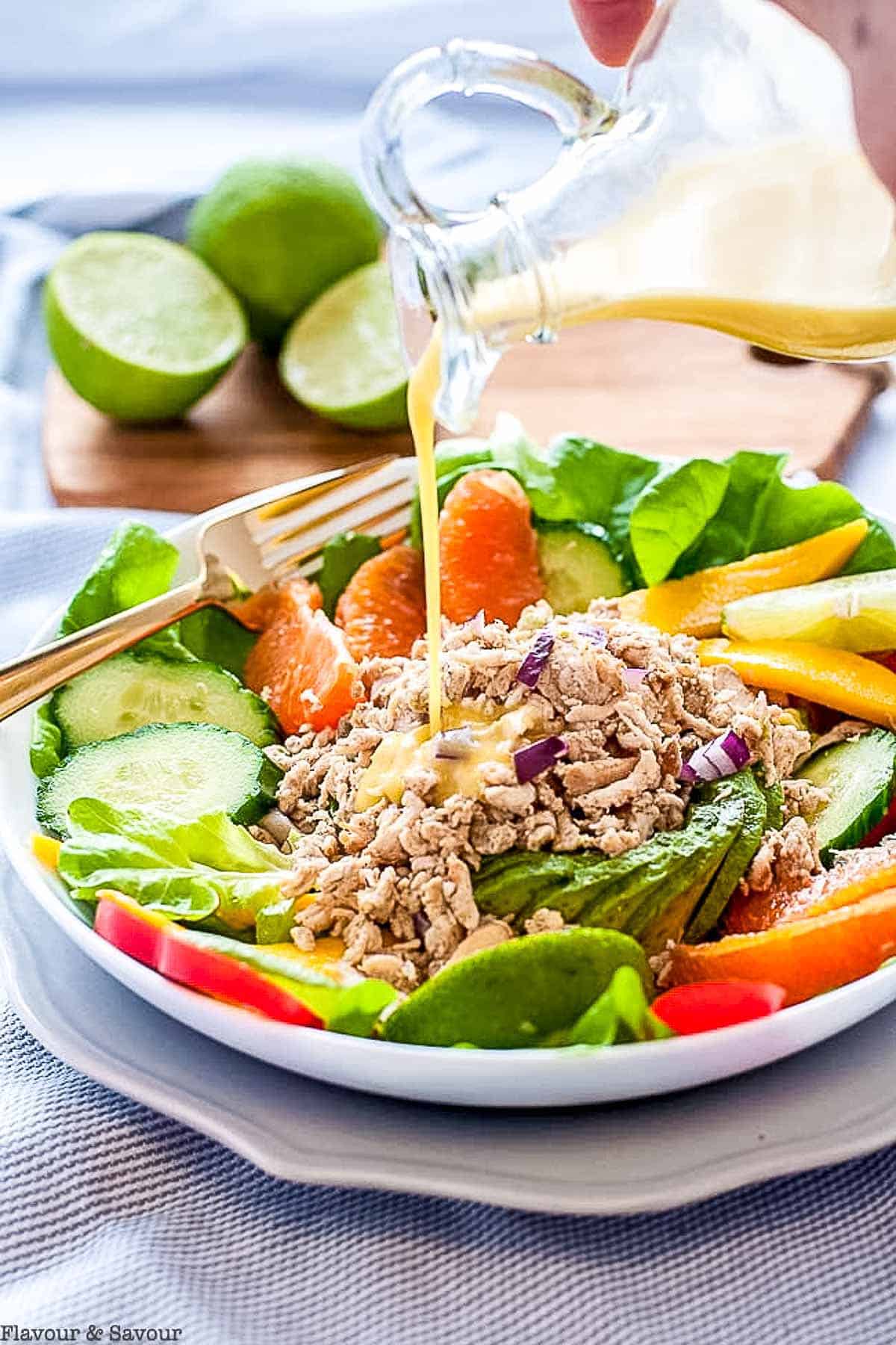 Adding dressing to Caribbean Shredded Jerk Chicken Salad.