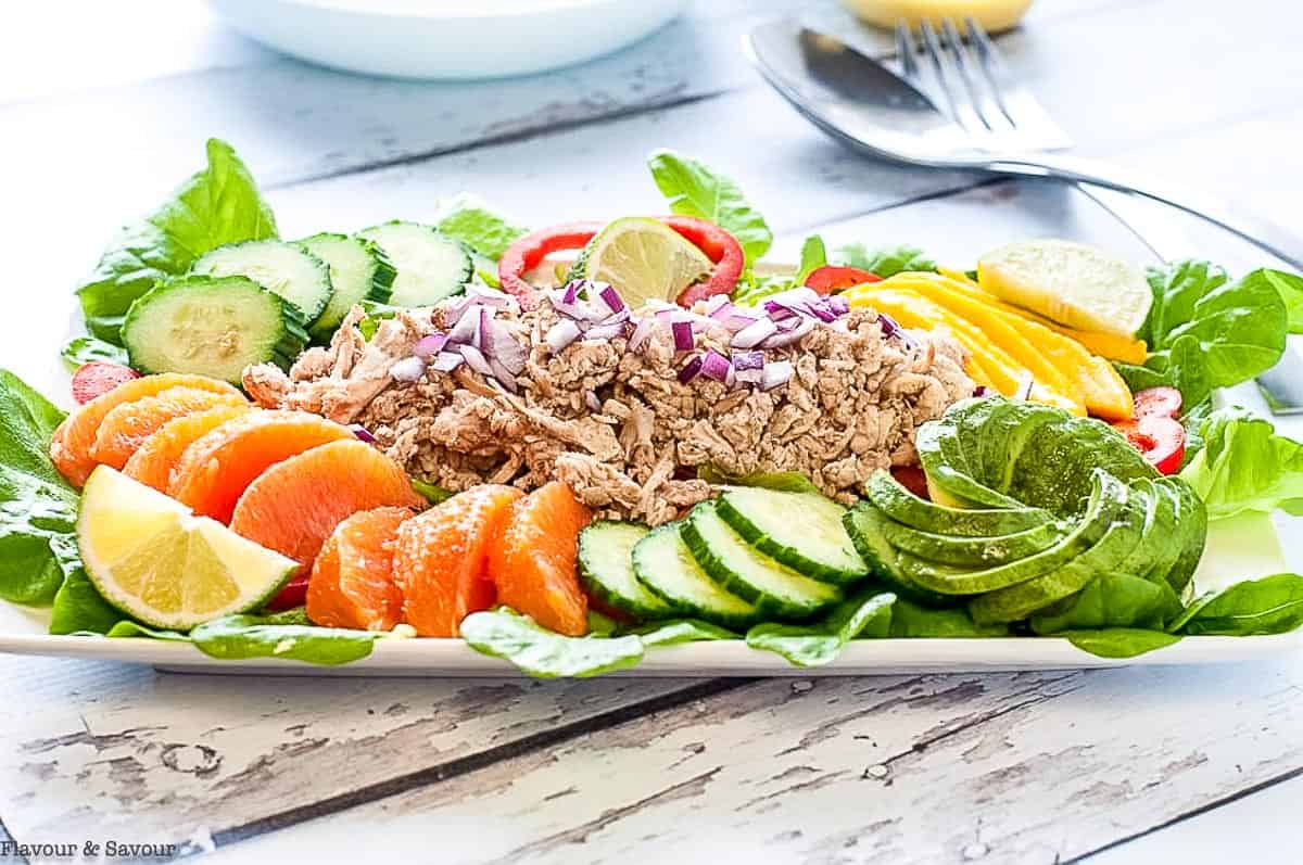 Caribbean Shredded Jerk Chicken Salad on a platter with fruit and avocado.