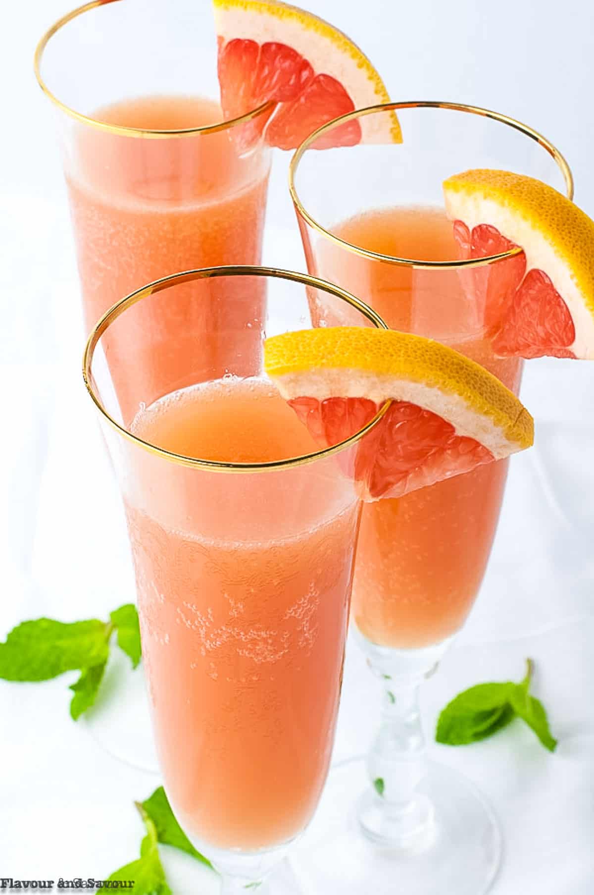 close up view of the tops of flutes with grapefruit ginger mocktail garnished with grapefruit slices