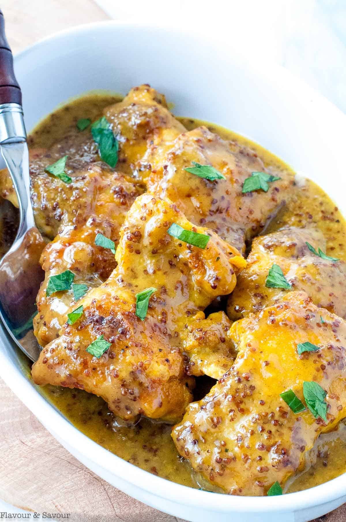 Honey Dijon Turmeric Chicken Thighs in a bowl with a spoon.