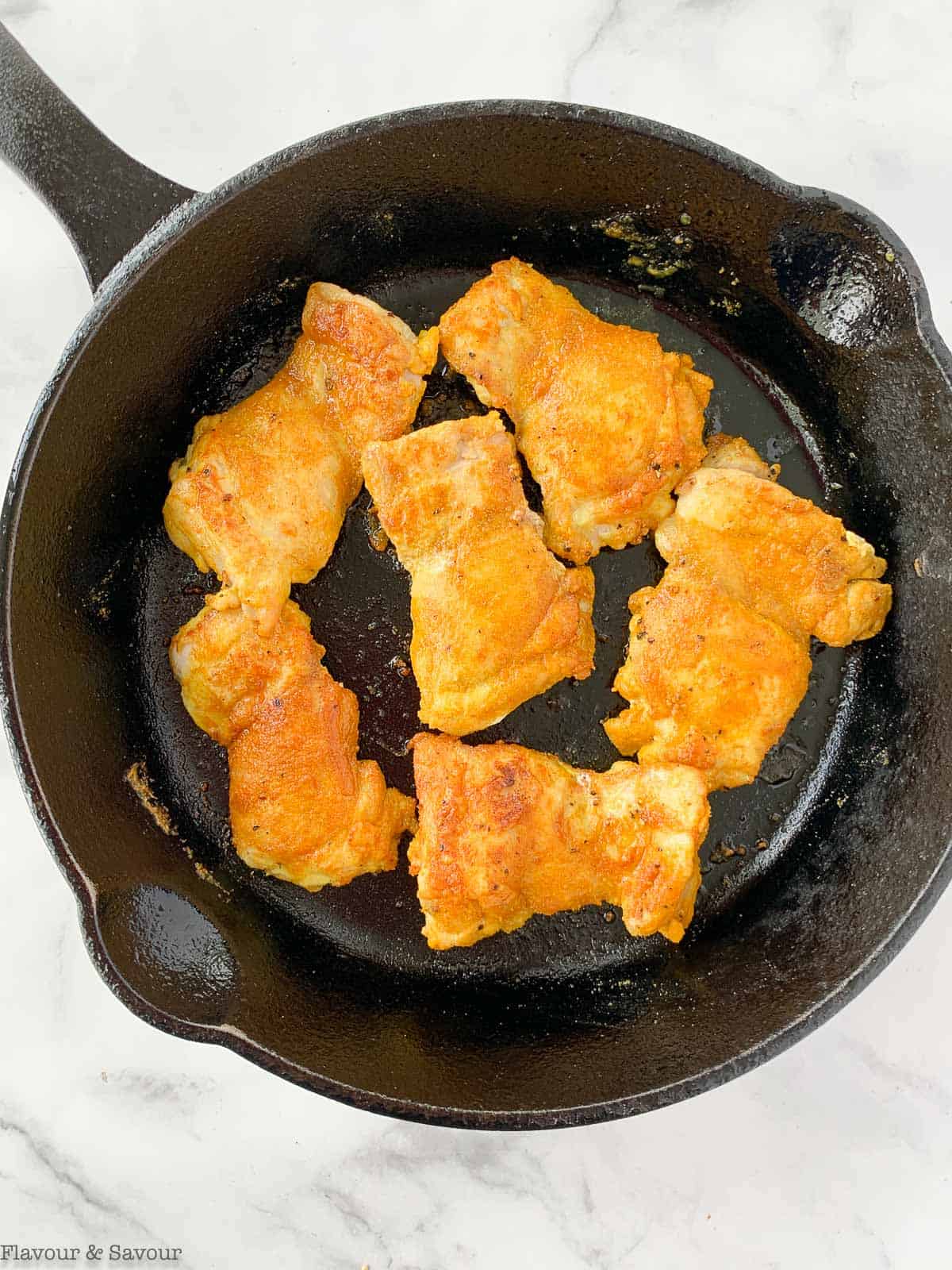 searing chicken thighs in skillet.