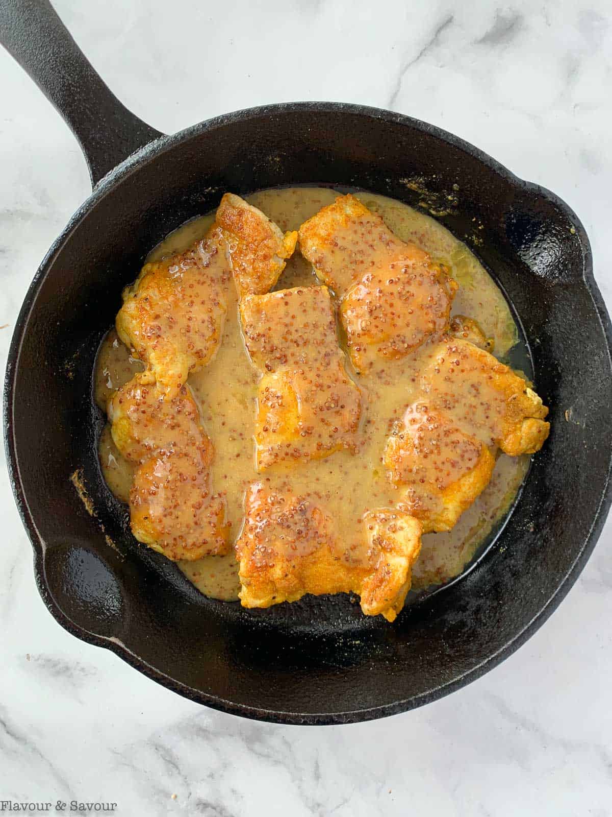 chicken thighs in sauce in skillet.