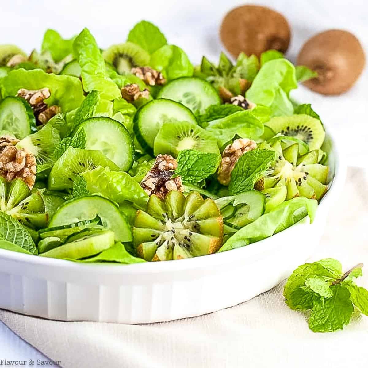 Kiwi cucumber green salad with butter lettuce, walnuts and fresh mint leaves.