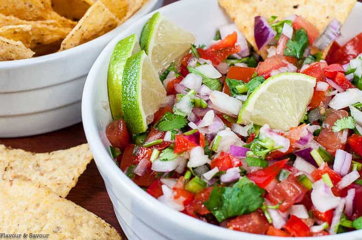 Salsa fresca (fresh salsa) in a bowl with lime wedges