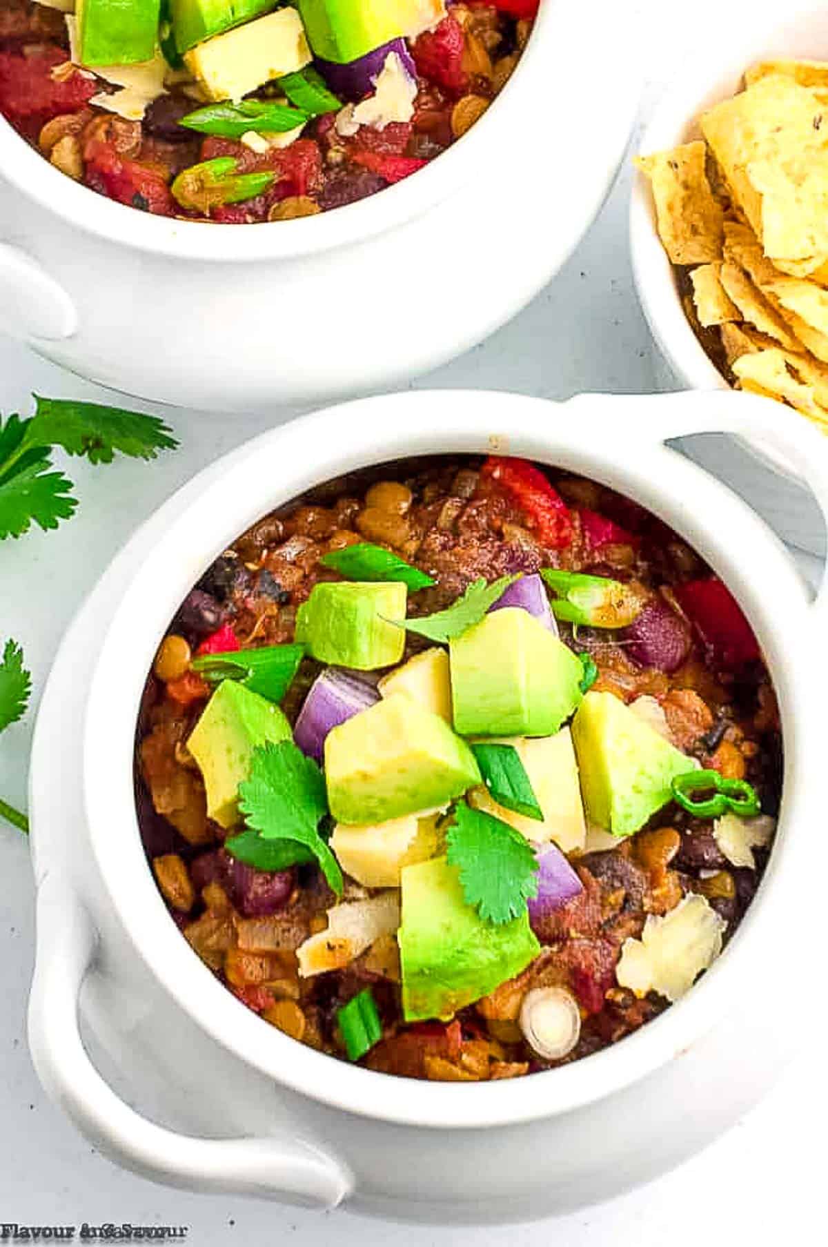 overhead view of a bowl of meatless chipotle chili with avocado cubes