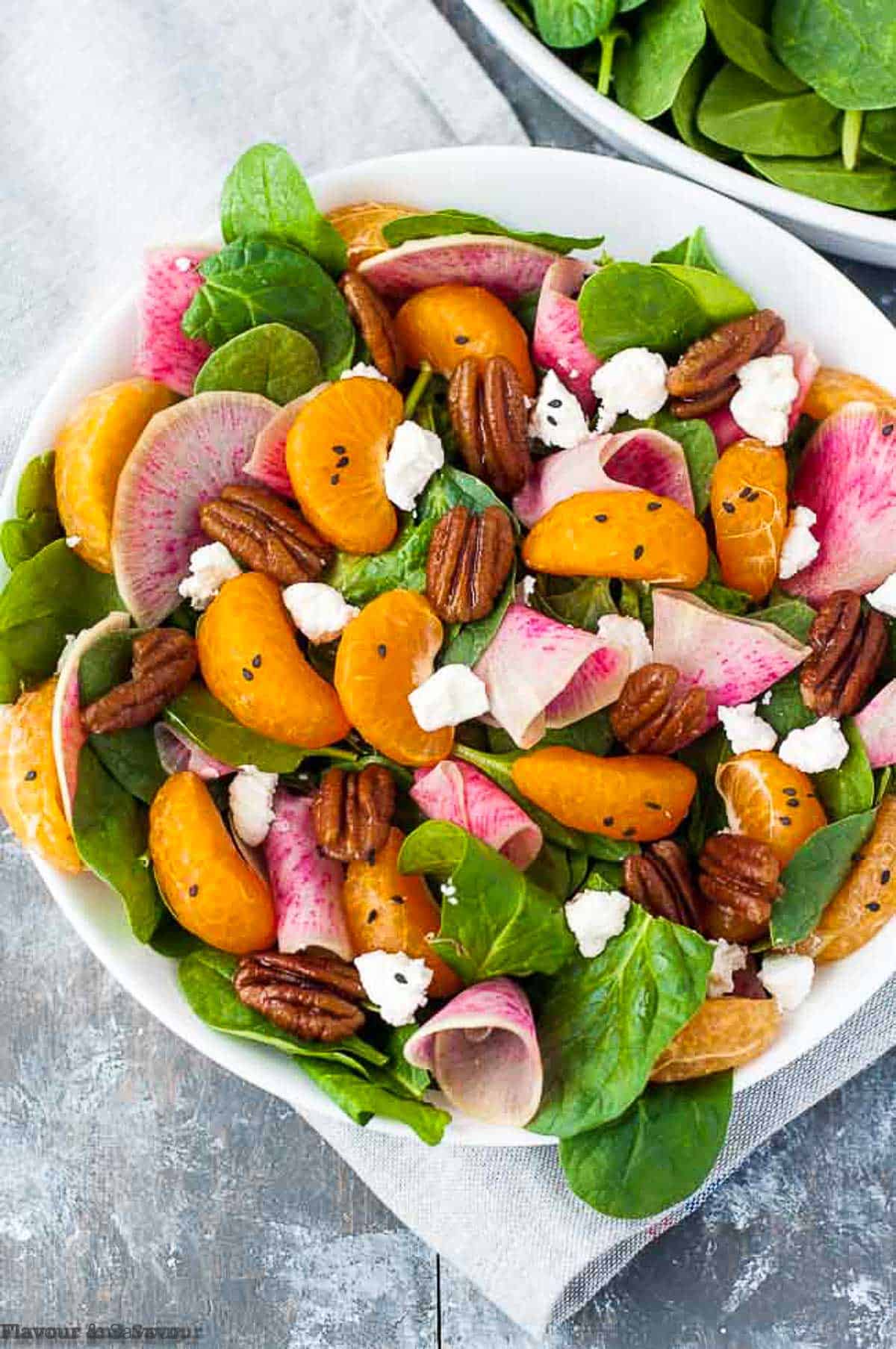 Watermelon radish and satsuma salad in a white bowl.