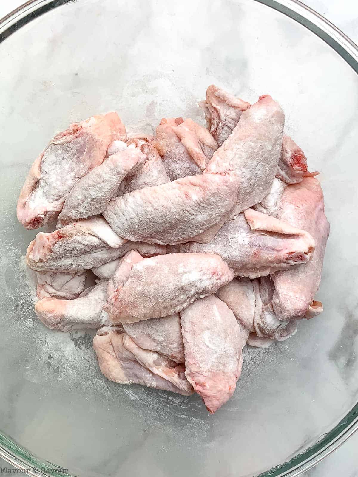 Raw chicken wings in a bowl with baking powder.
