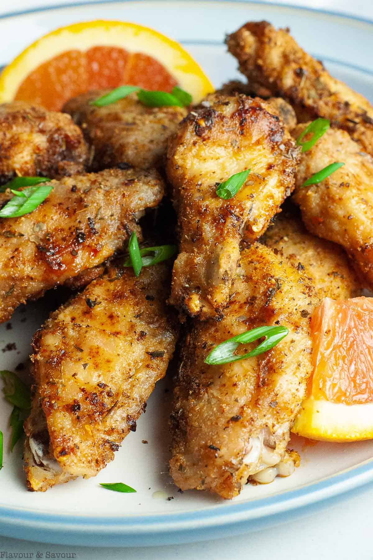 A plate filled with air fryer crispy Cajun chicken wings garnished with green onions.