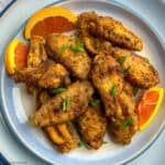 Overhead view of a plate of Cajun spiced chicken wings with orange slices