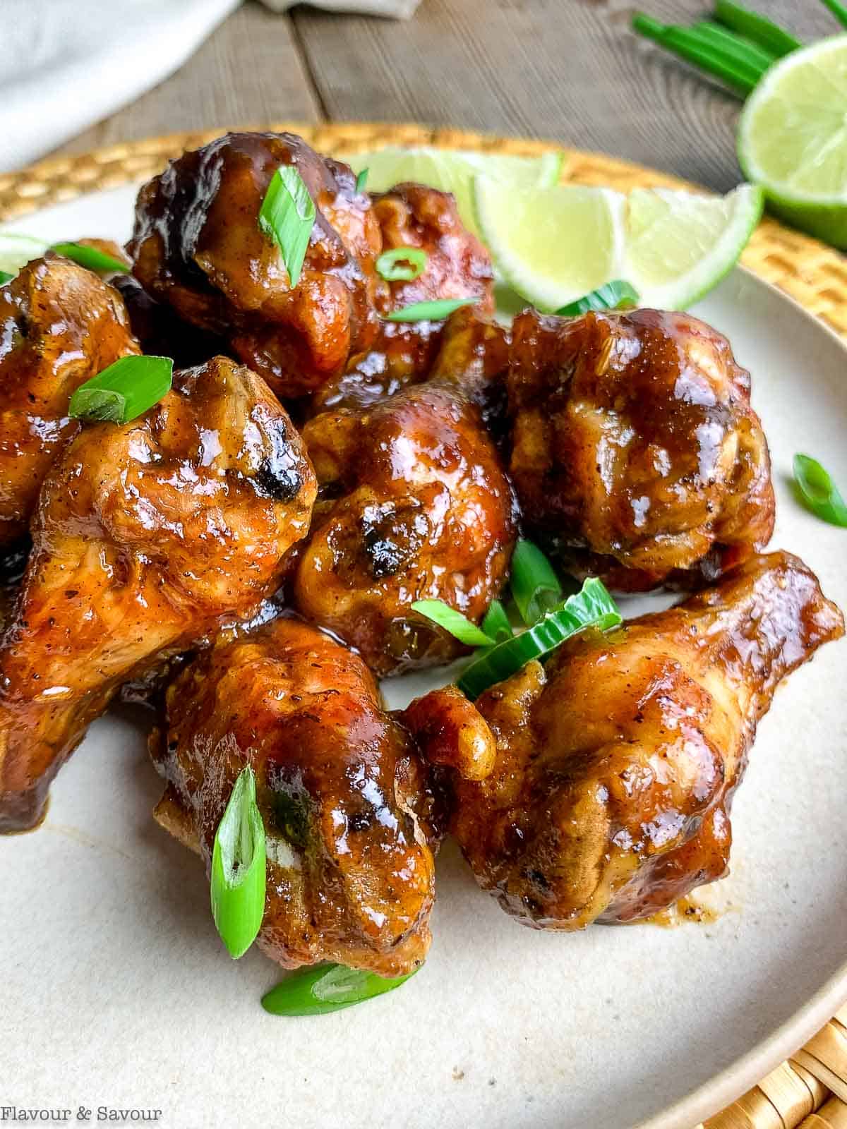 Close up view of jerk chicken wings garnished with green onions and jalapeño slices.