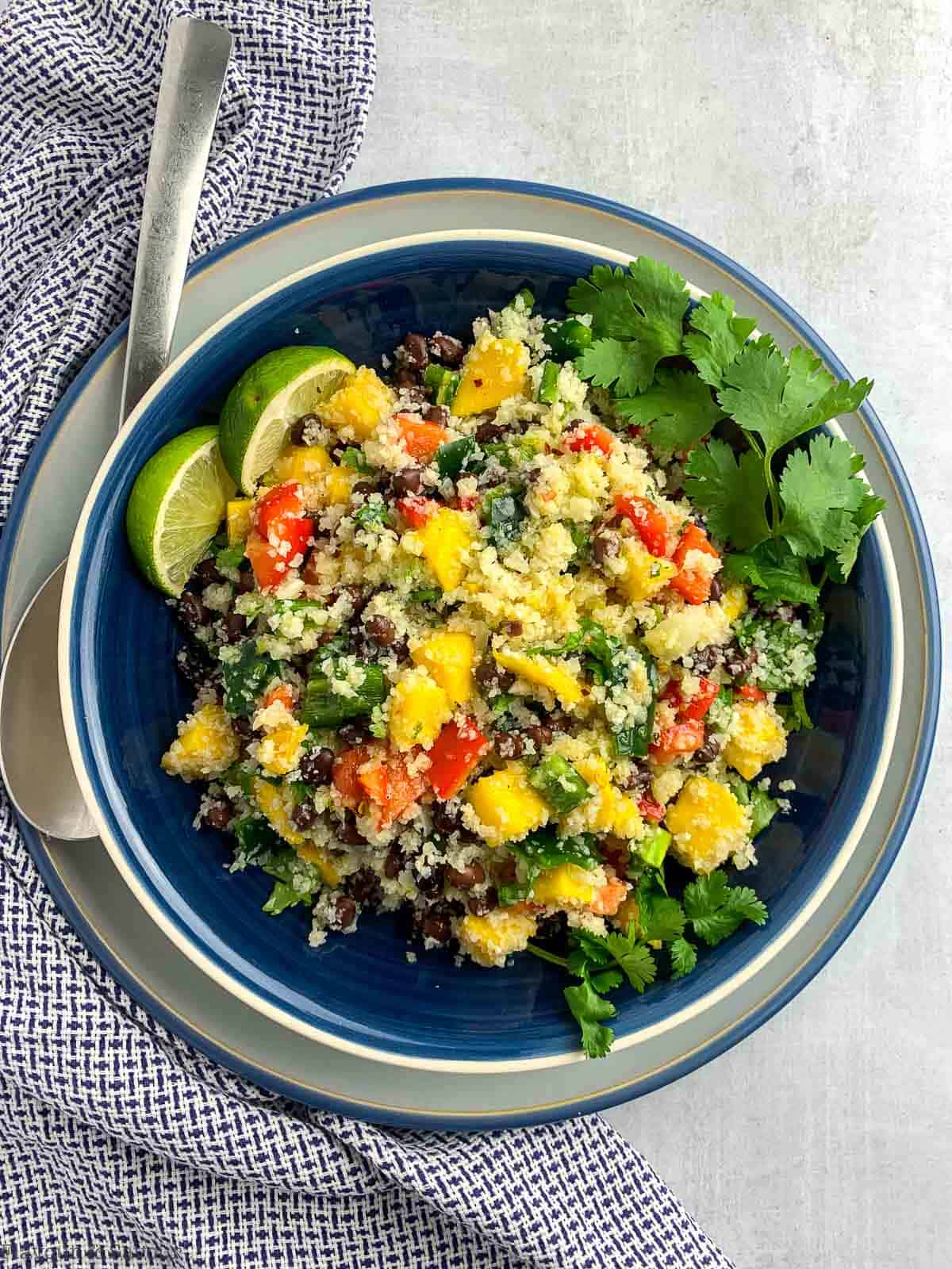 a large blue bowl filled with cauliflower couscous salad