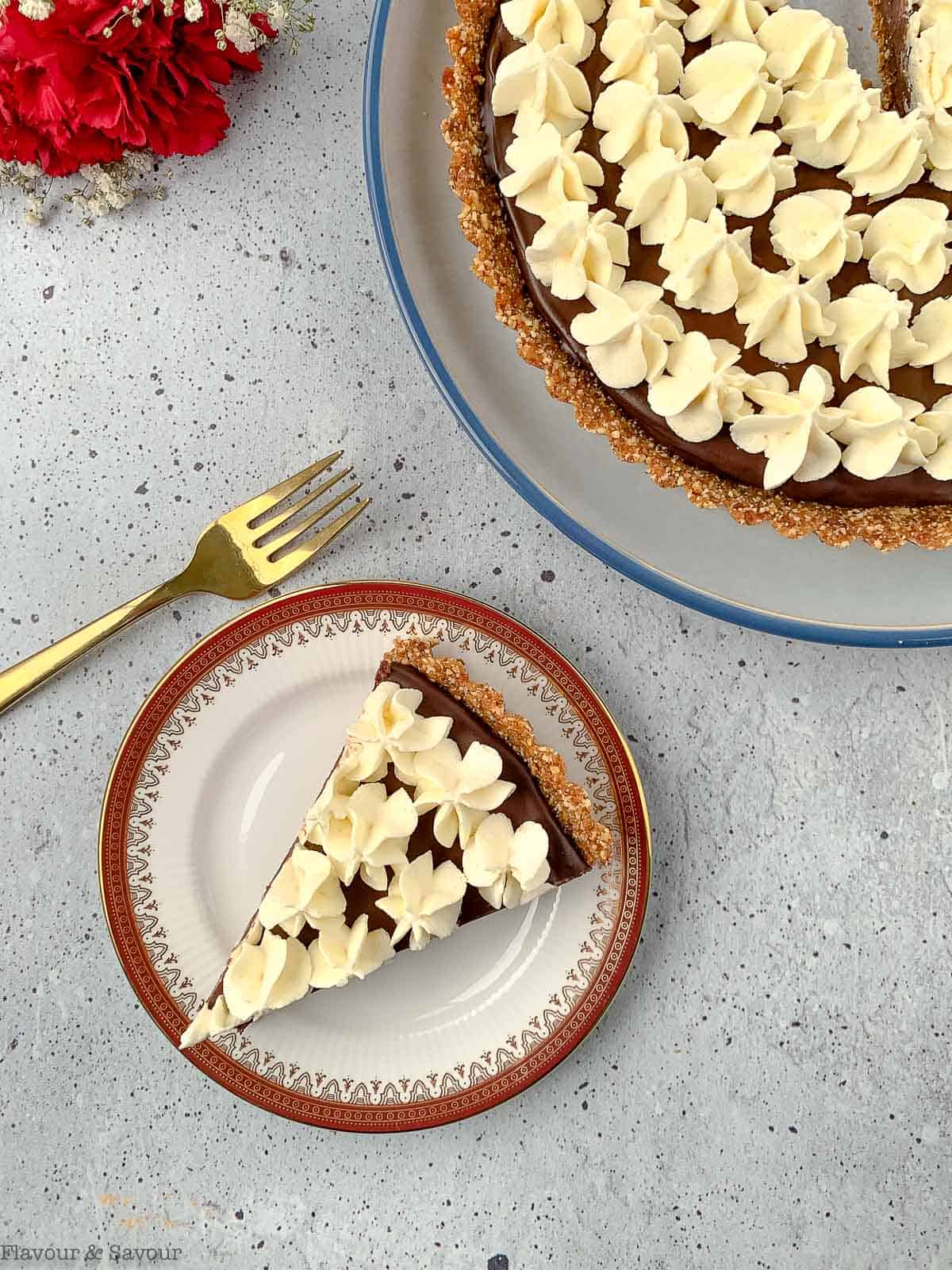 A slice of chocolate ganache tart next to a whole tart.