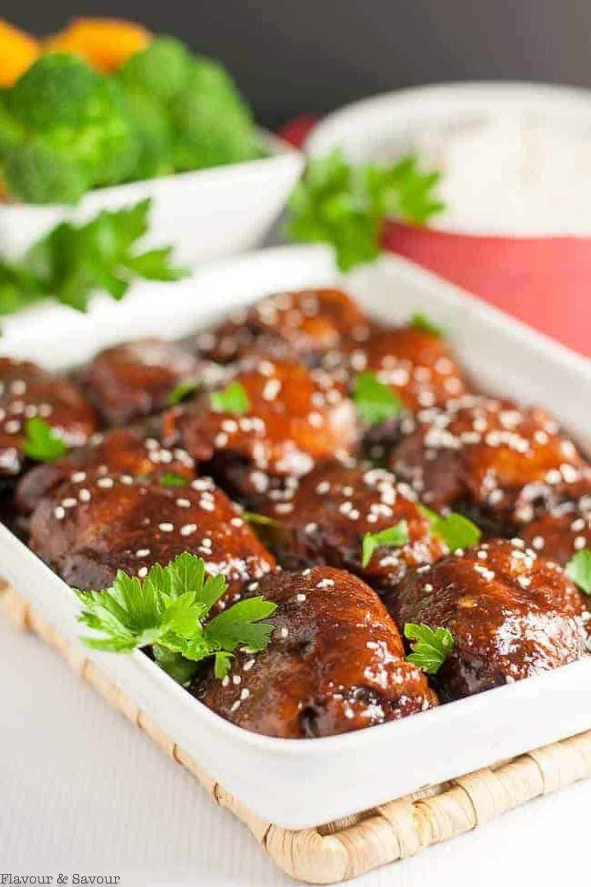 A white baking dish with 10 sticky chicken thighs cooked in a slow cooker.