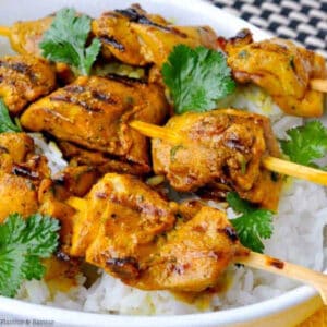grilled turmeric chicken kabobs on a bed of rice