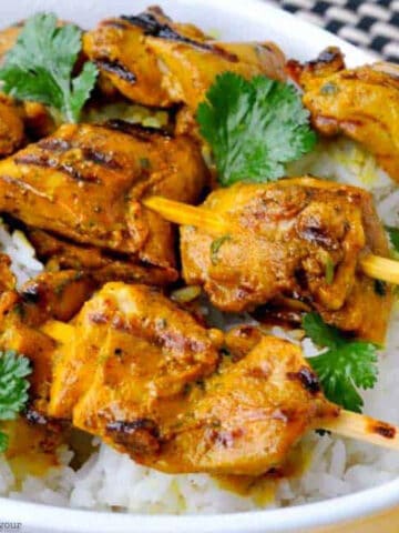 grilled turmeric chicken kabobs on a bed of rice