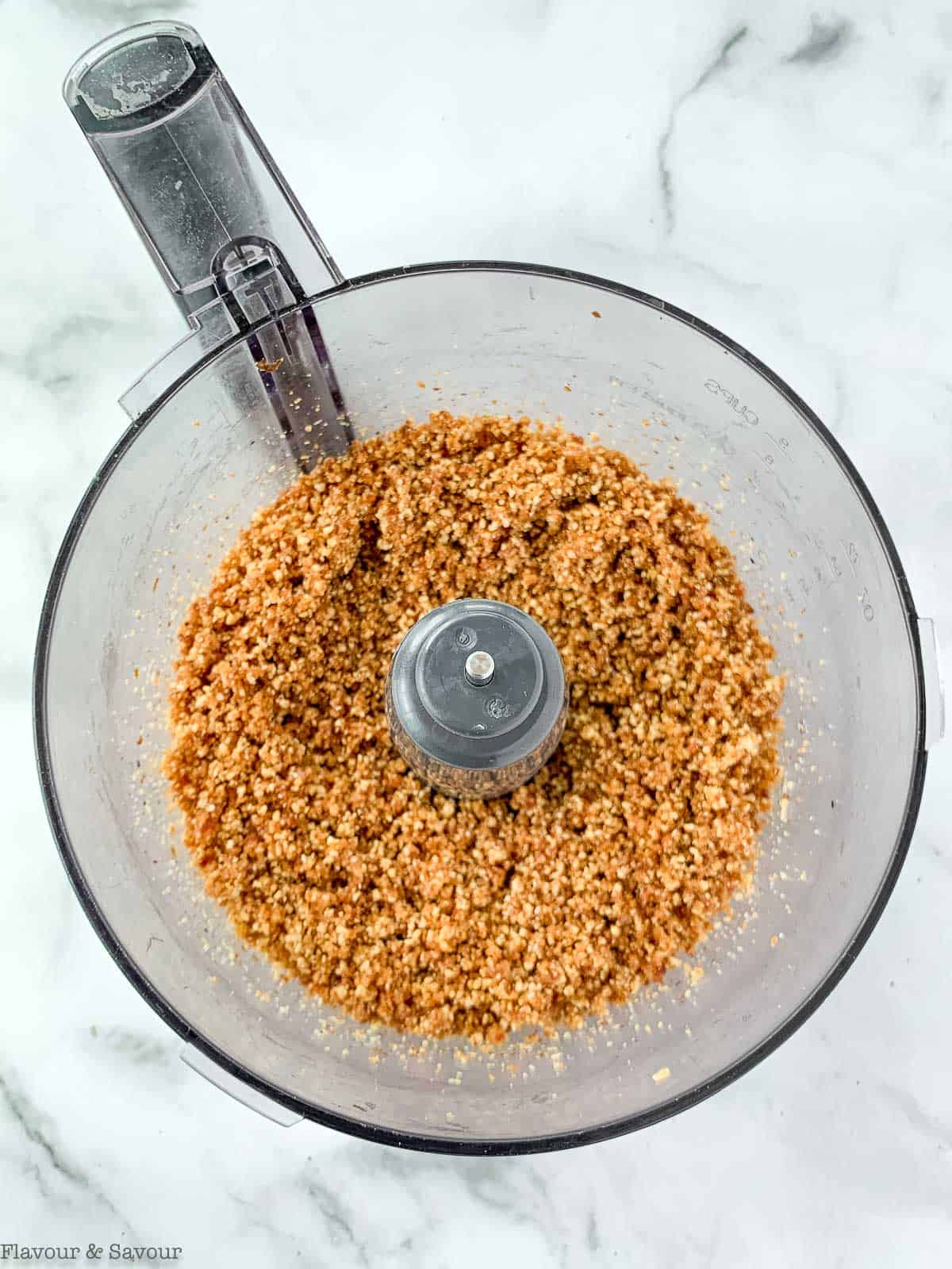 Finely ground hazelnuts in a food processor bowl.