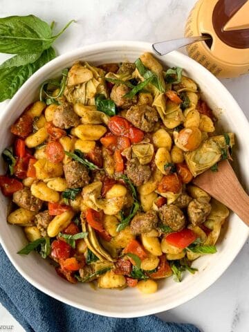 overhead view of a round bowl of gnocchi with pesto and vegetables