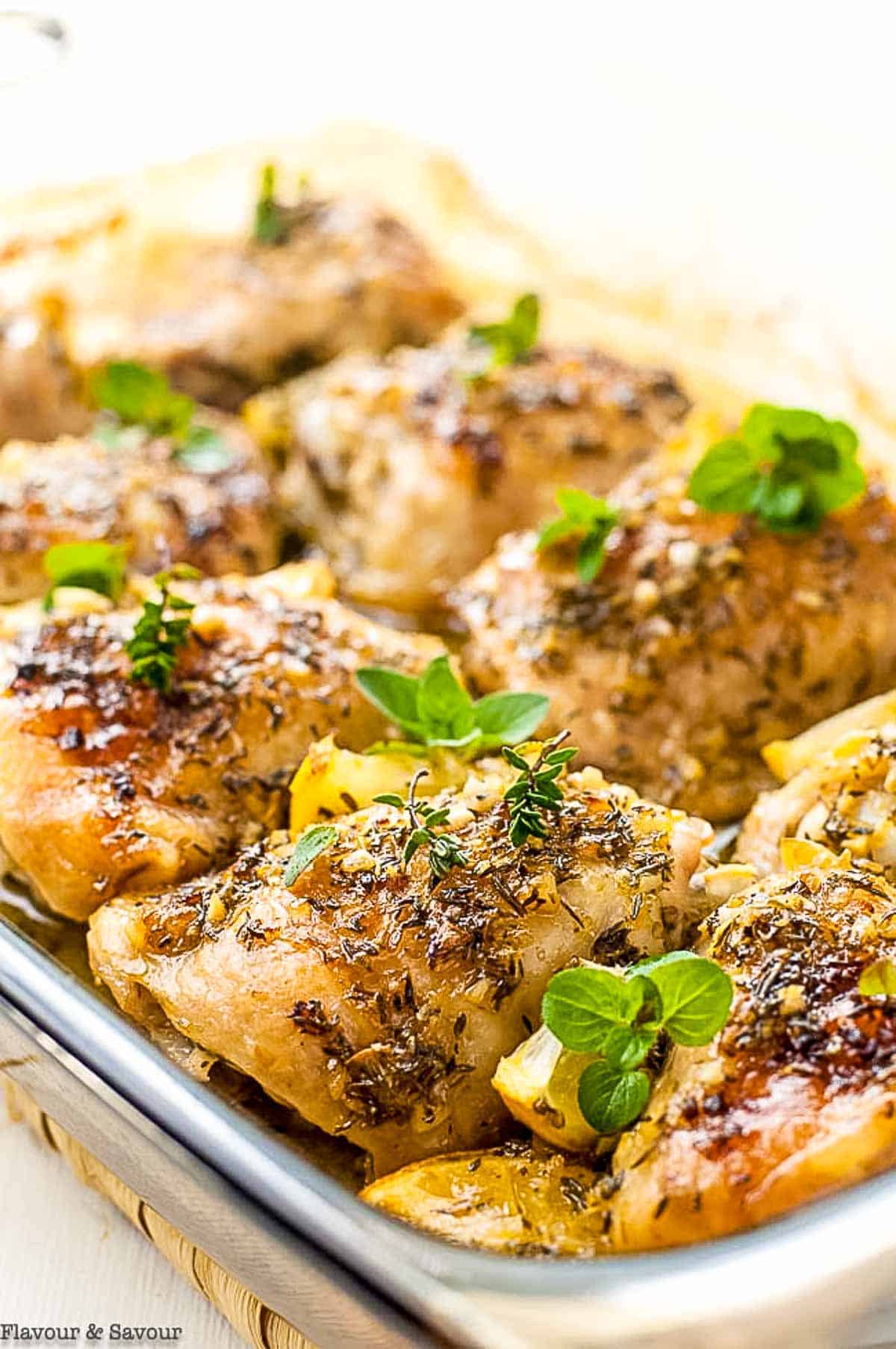 a baking tray wil baked lemon chicken thighs with lemon and herbs