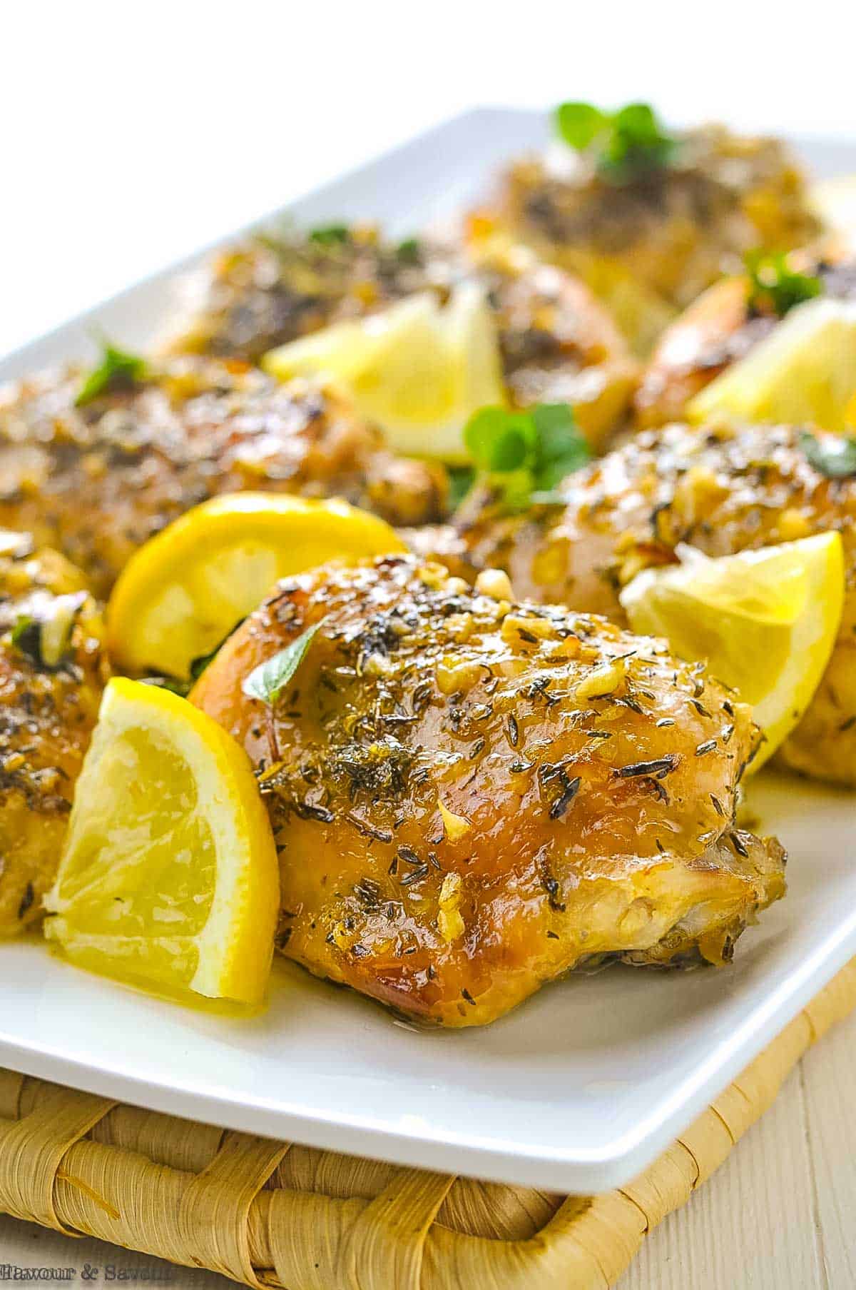 Easy Baked Lemon Chicken thighs on a serving platter with lemon wedges.