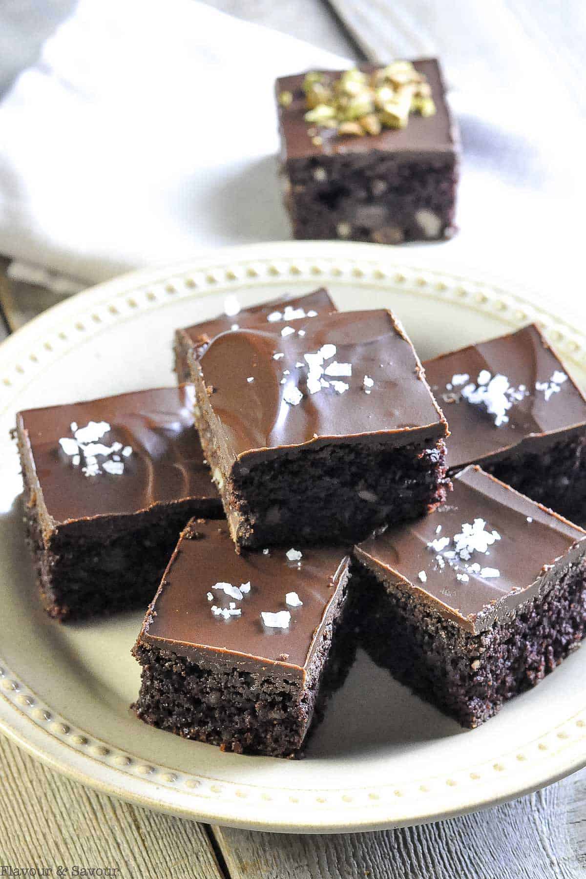 brownies with ganache topping stacked on a plate 